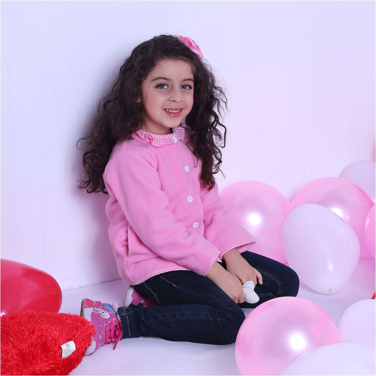 A little girl wearing fleece jacket lined in soft pink cotton, with pink gingham edging and a neckline ruffle