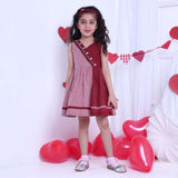 A girl in red checked dress with a hand-smocked band of hearts in a crossover style, with a V-neck and cord piping trims