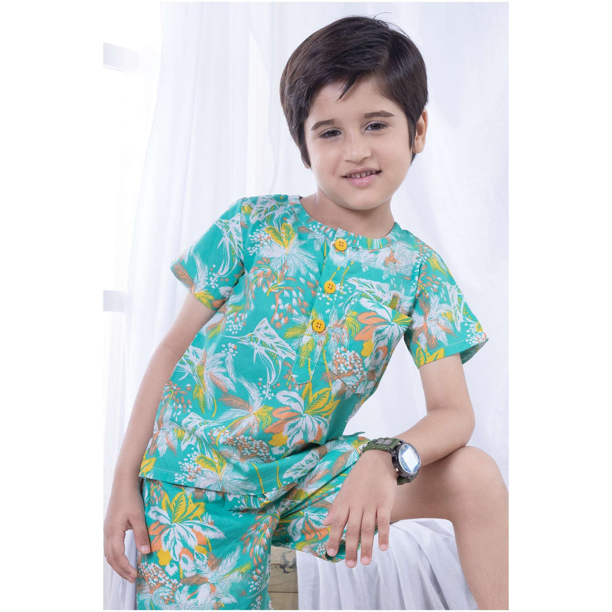 Boy wearing an aqua palm tree print polo shirt and matched bermuda shorts