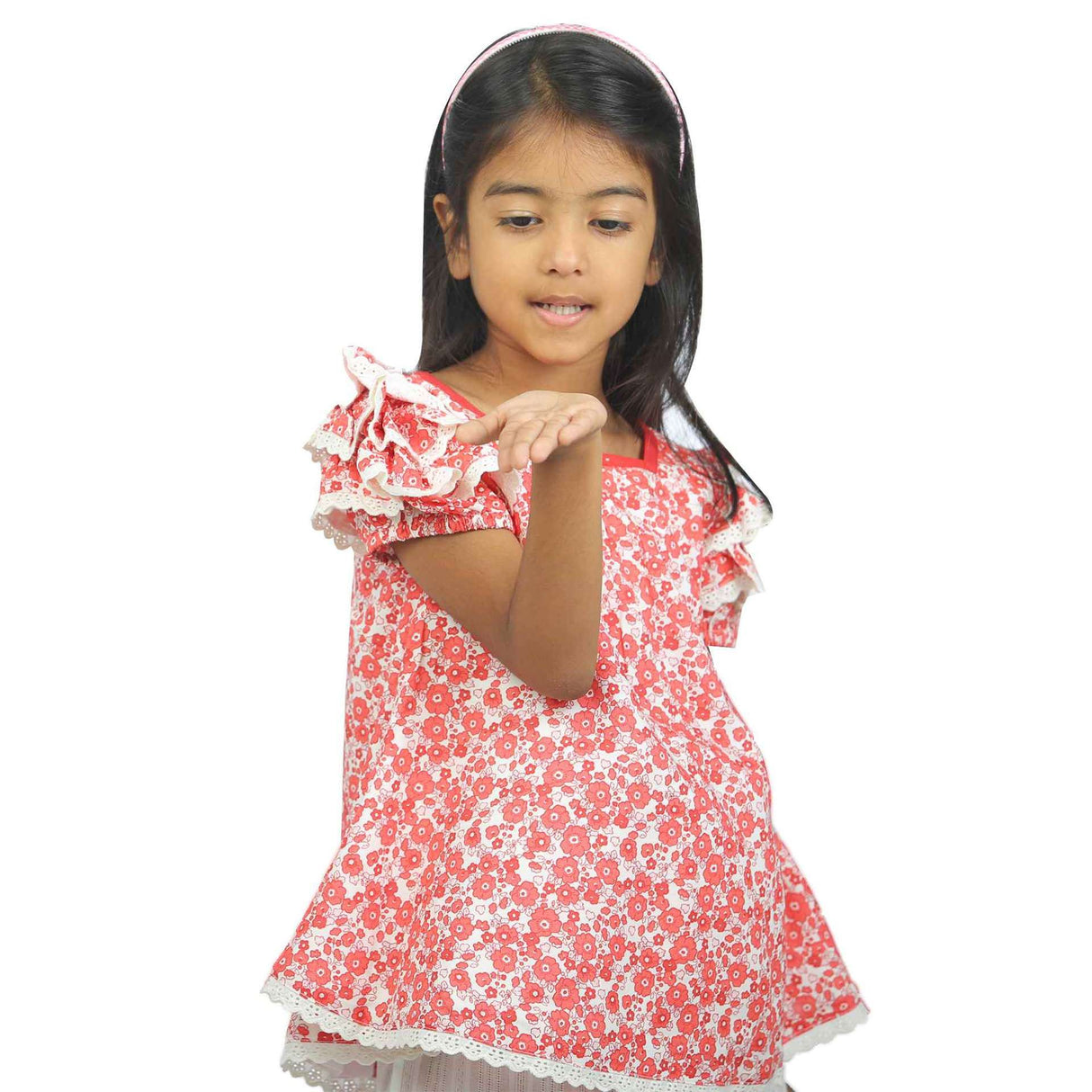 Girl wearing a coral floral print tunic with ruffle trimmed gathered sleeves