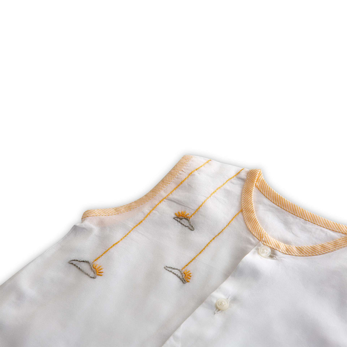 Close up of hand embroidered details on white muslin jabla with contrast piping