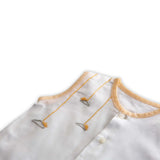 Close up of hand embroidered details on white muslin jabla with contrast piping