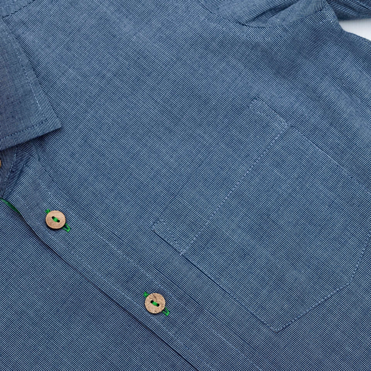 Close up of blue button down shirt with front pocket and wood buttons down the front