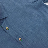 Close up of blue button down shirt with front pocket and wood buttons down the front