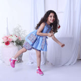 A girl in blue double gauze cotton tunic with floral ruffled neckline and tie-up belt paired with matching floral shorts