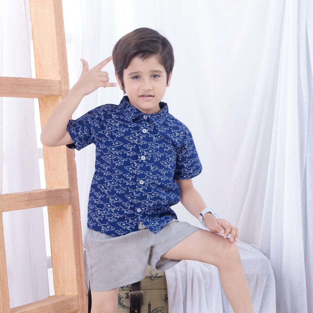 Boy wearing a dark blue shark print casual half sleeve shirt with grey shorts