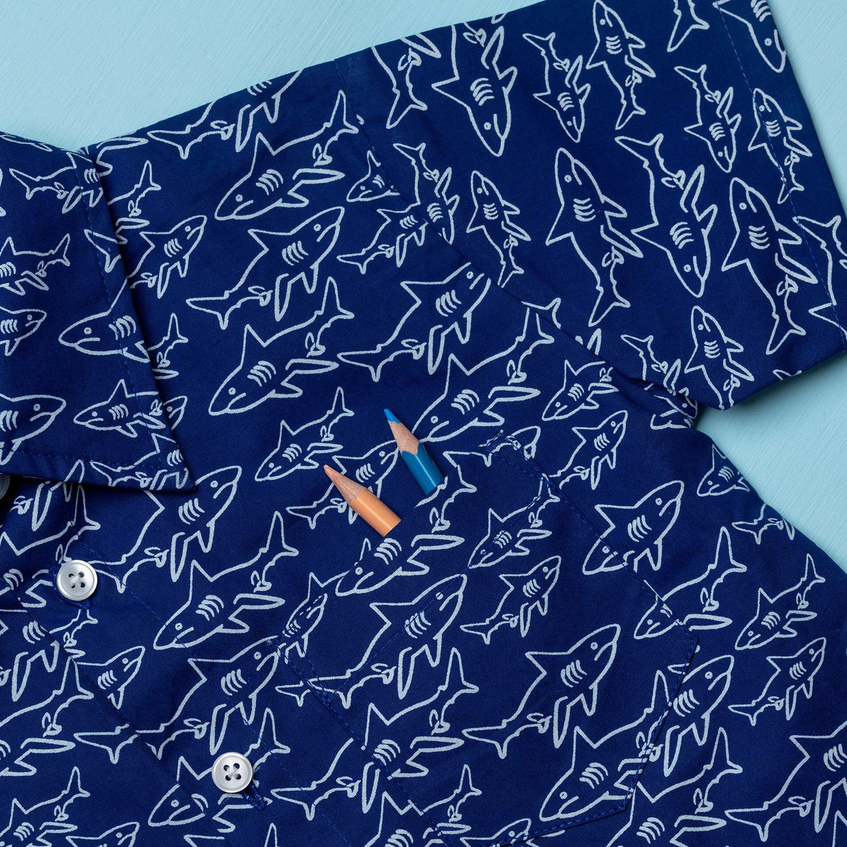 Close-up of navy blue boy's shirt in shark print with buttons down the frontv