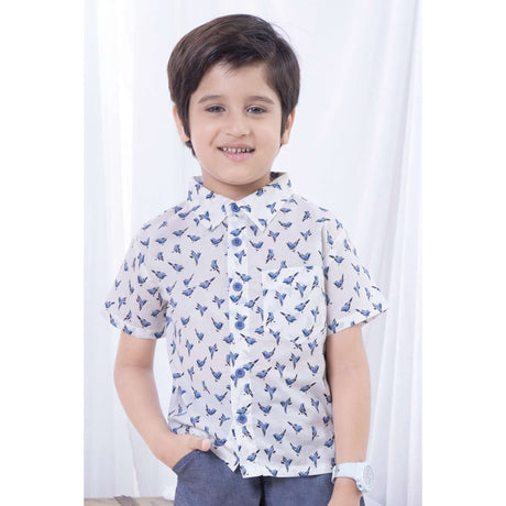 Boy wears a bird print half sleeve shirt and smiles