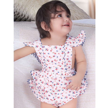 A baby girl in blue floral printed onesie with back crossover straps and ruffles on the bottom with contrast trims