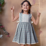 A young girl showcasing striped sleeveless dress with charming side bows and delicate lace trims