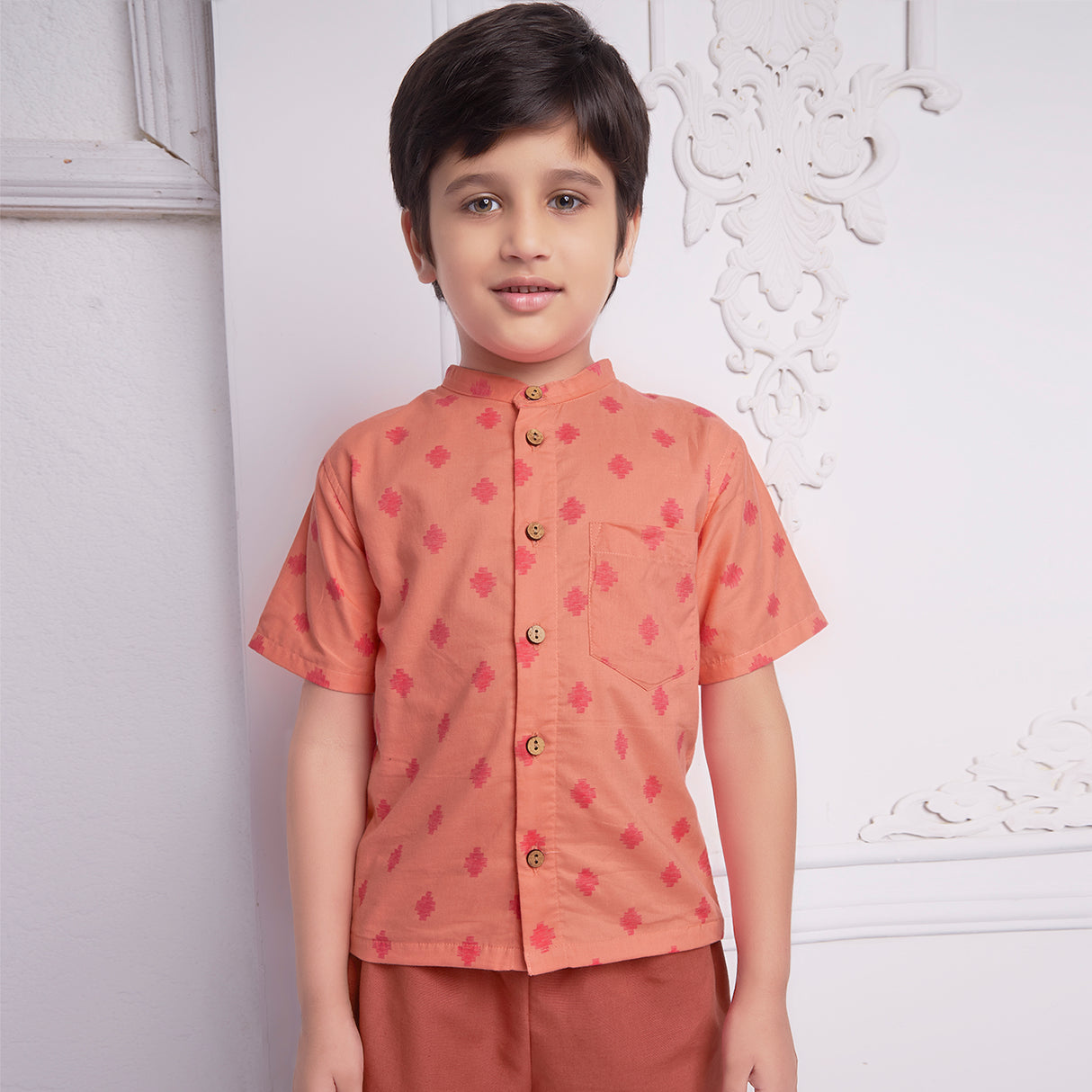 front view of boy wearing a orange geometric print shirt