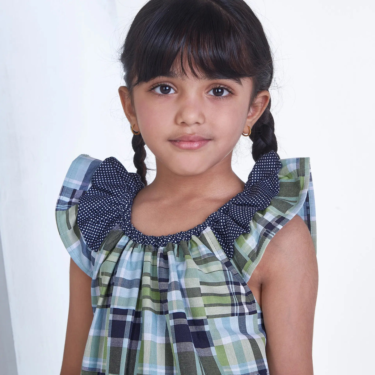 Closeup of a girl dressed patch printed fabric dress in tones of navy, turquoise and green adorned with flutter sleeves