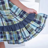 Closeup of the hem of a patch printed fabric dress in tones of navy, turquoise, and green