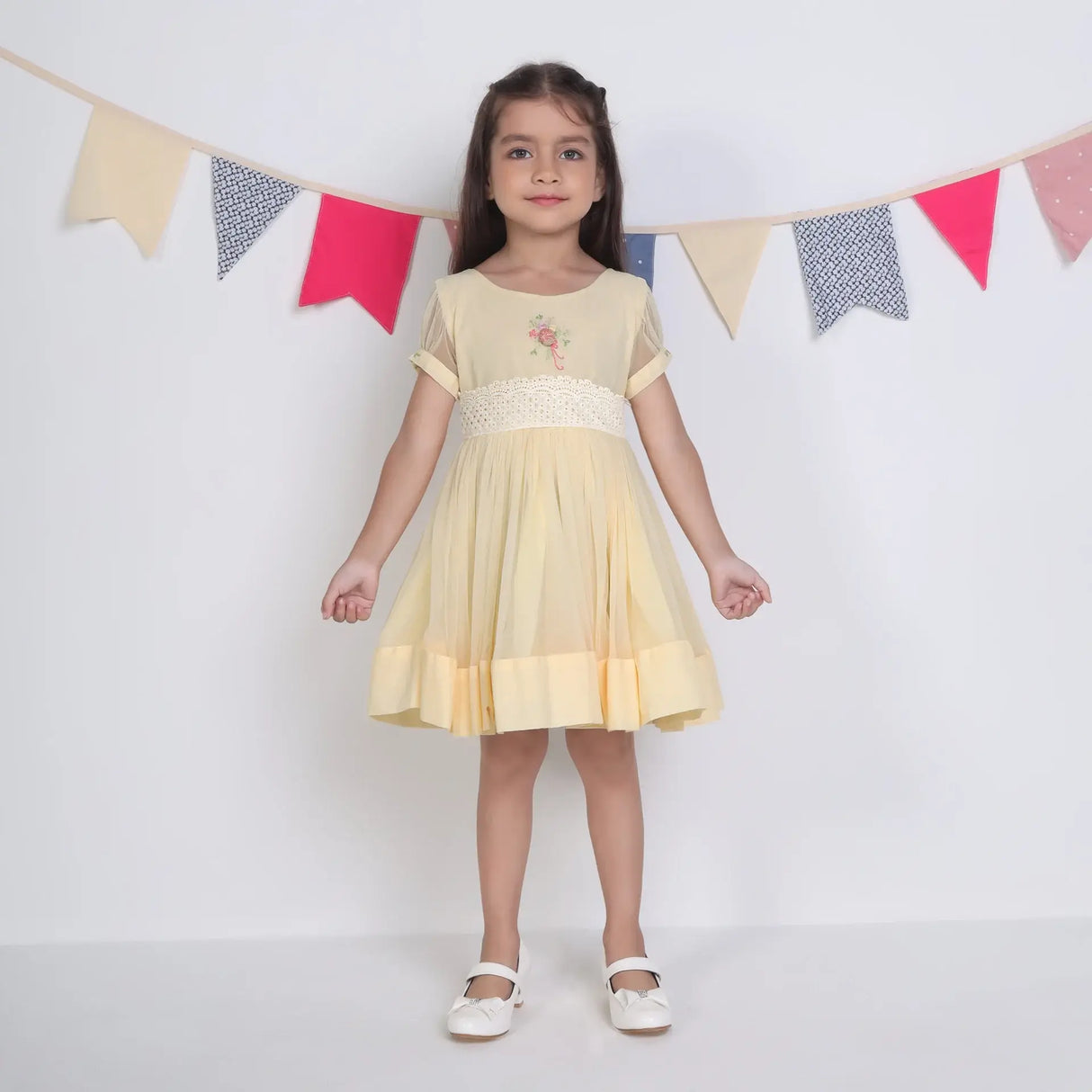 "A little girl wearing a yellow hand-embroidered tulle dress."