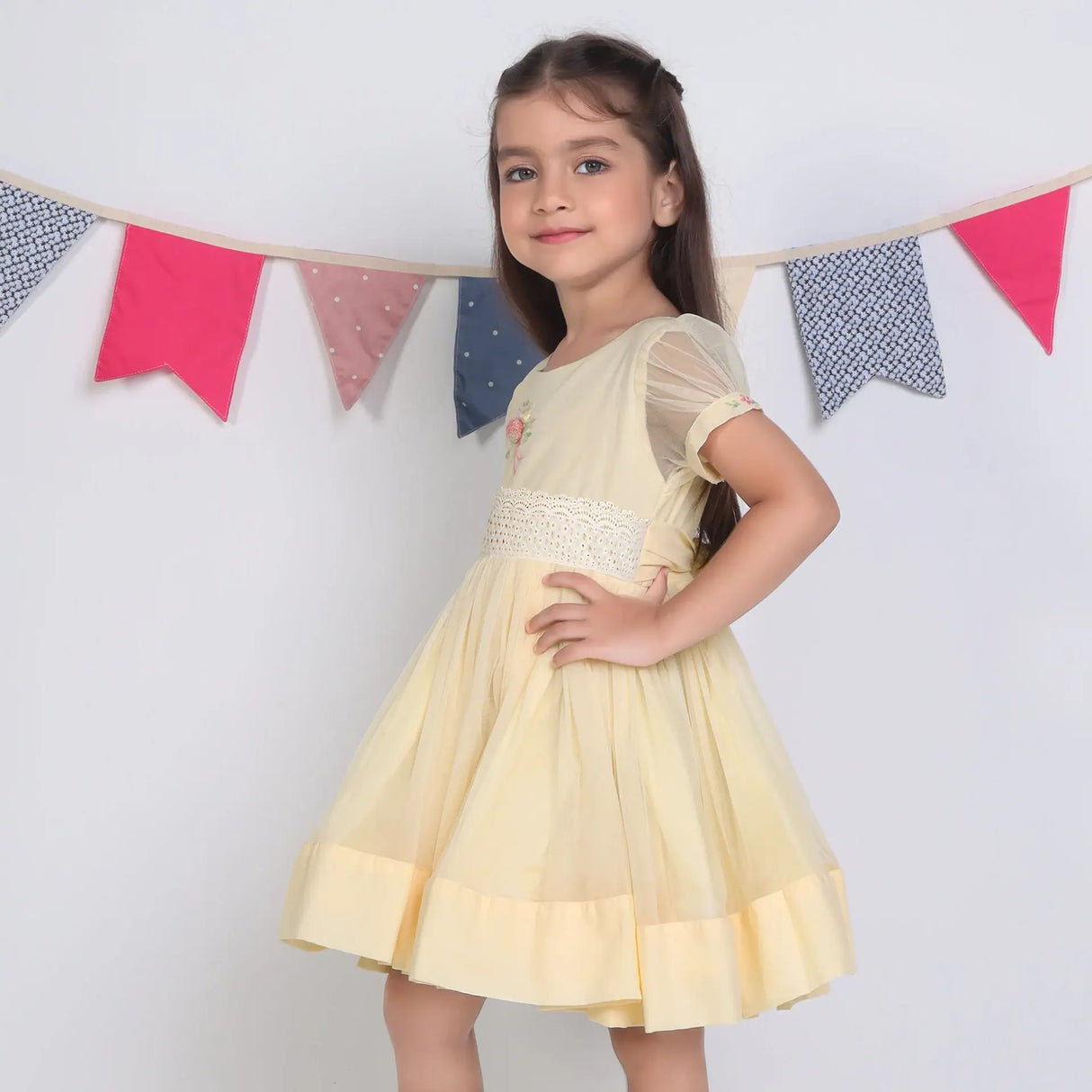 "Side view of a girl in a yellow hand-embroidered tulle dress."