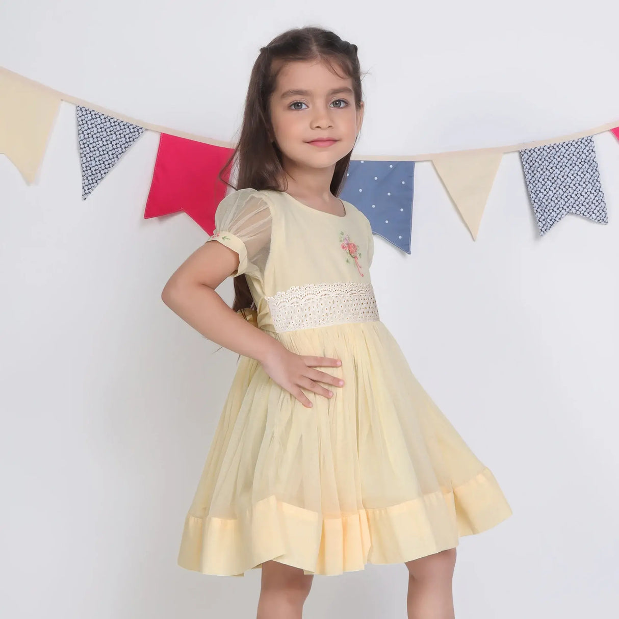 "Side view of a girl in a yellow hand-embroidered tulle dress."