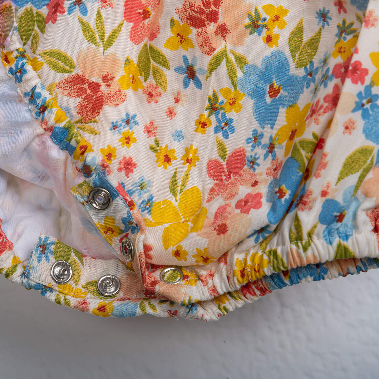 Close-up of snap buttons on an ivory floral printed baby girl onesie from Soleilclo.