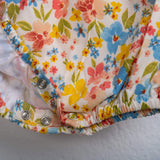 Close-up of snap buttons on an ivory floral printed baby girl onesie from Soleilclo.