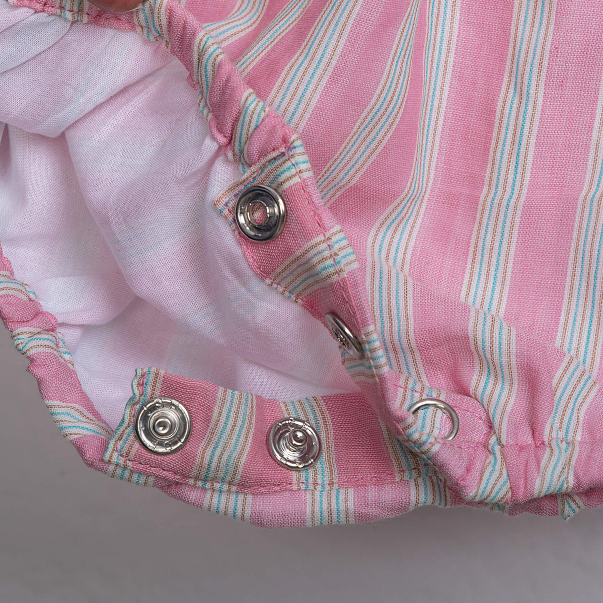 Close-up of snap buttons on pink striped embroidered baby girl onesie from Soleilclo