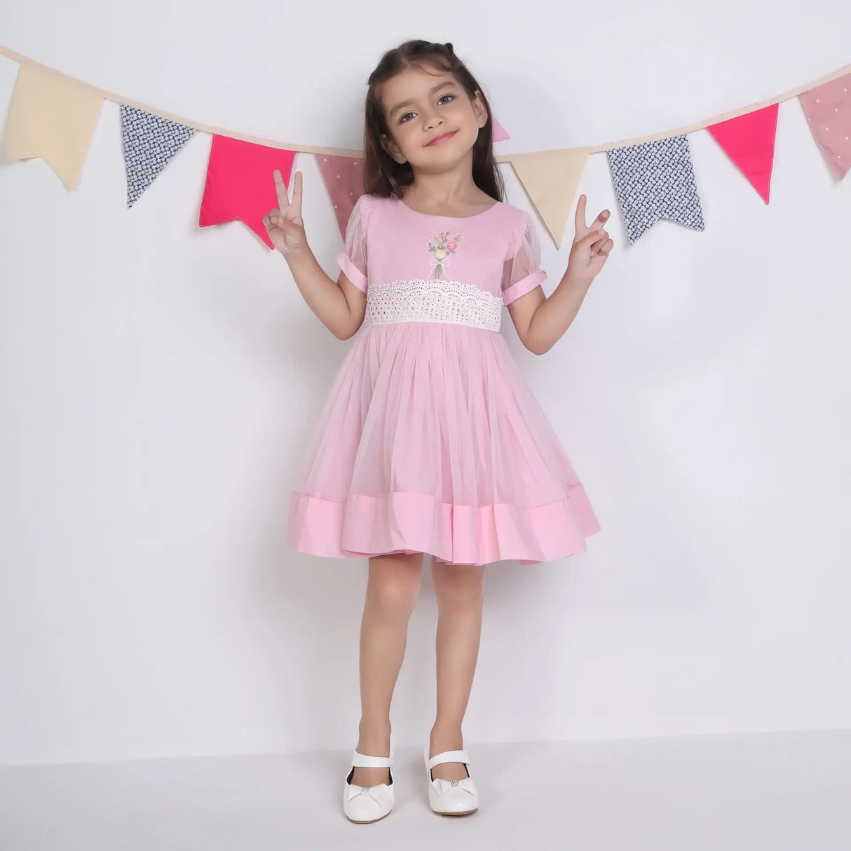 "A little girl posing in a pink hand-embroidered tulle dress."