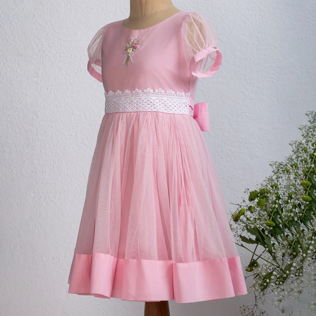 "Side view of a mannequin in a pink hand-embroidered tulle dress."