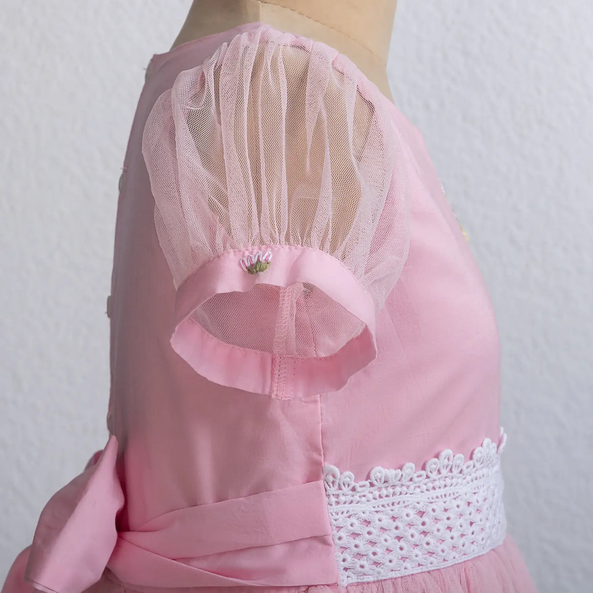 "Close-up of the floral hand embroidery on the puff sleeve of a pink tulle dress."