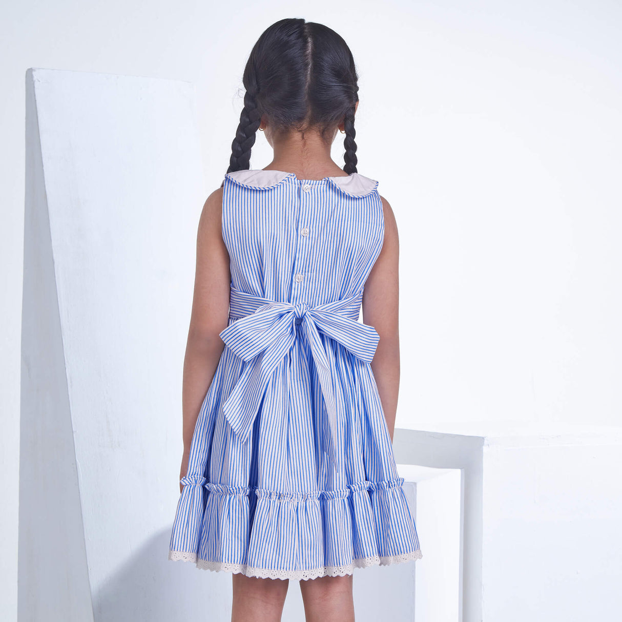 A girl seen from behind wearing a blue striped embroidered collared dress