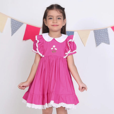A little girl dressed in a pink embroidered cotton puffed sleeves dress.