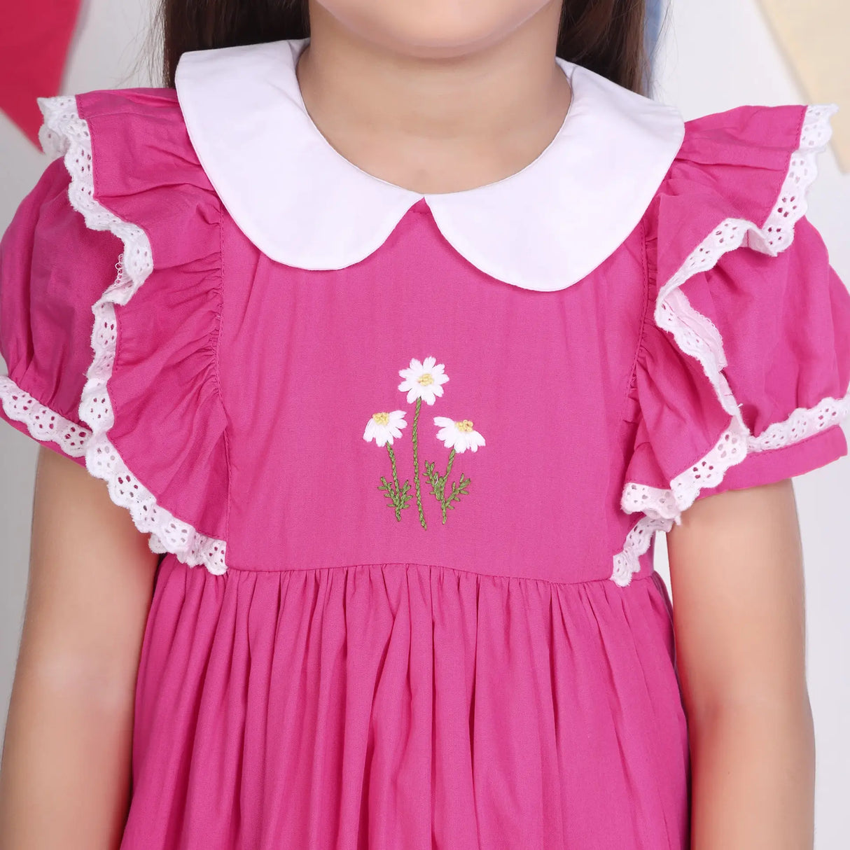 Close-up of the embroidery details on the pink cotton puffed sleeves dress.