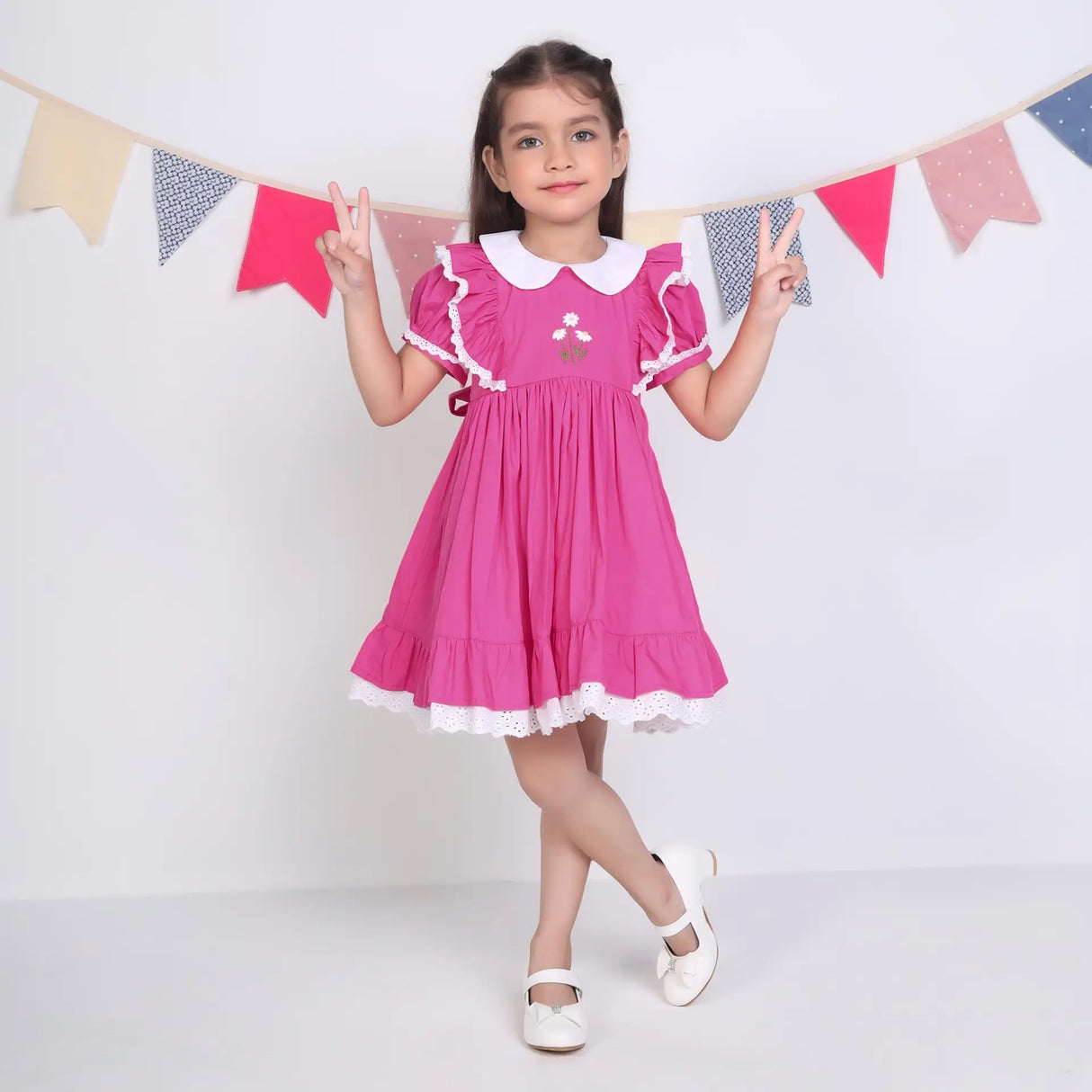 A little girl dressed in a pink embroidered cotton puffed sleeves dress.