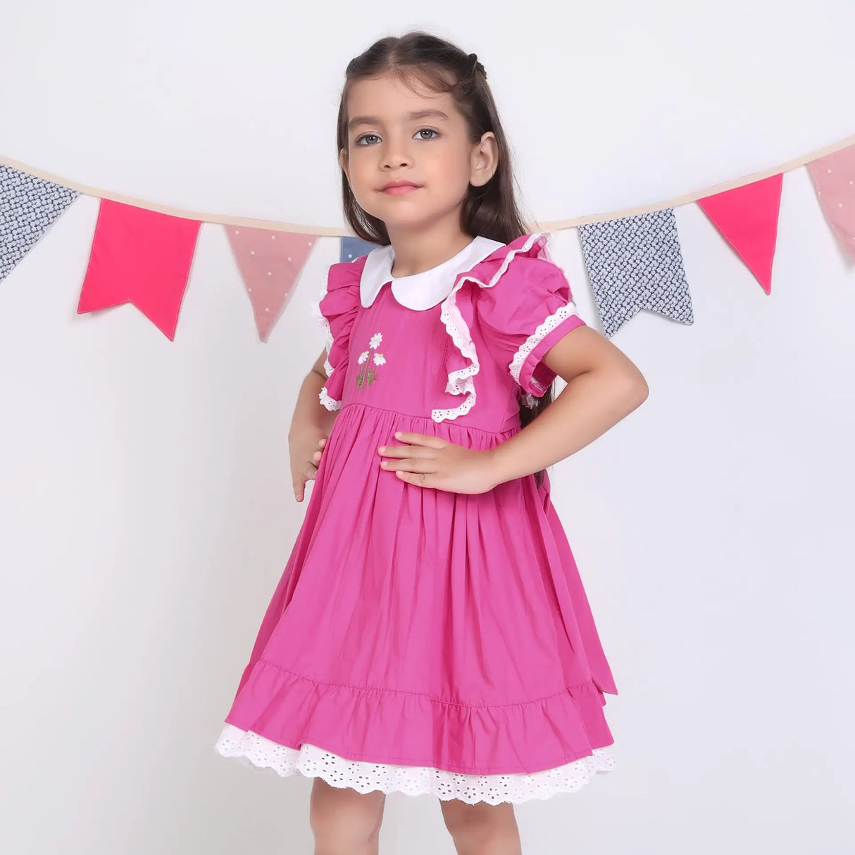 Side view of a girl in a pink embroidered cotton puffed sleeves dress.