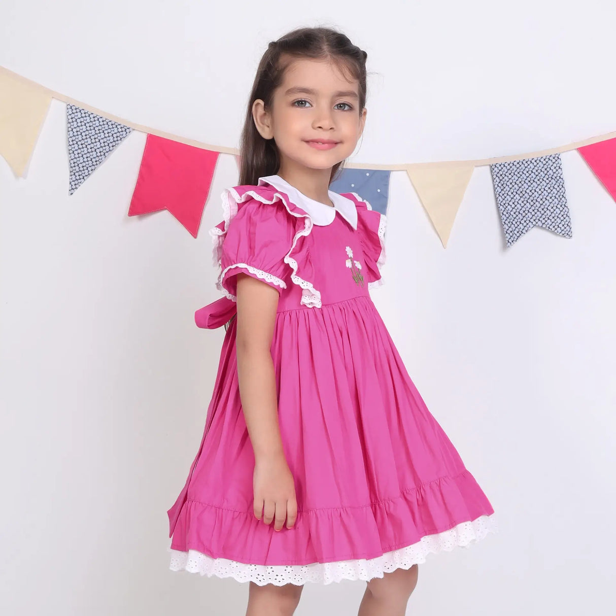 Side view of a girl in a pink embroidered cotton puffed sleeves dress.