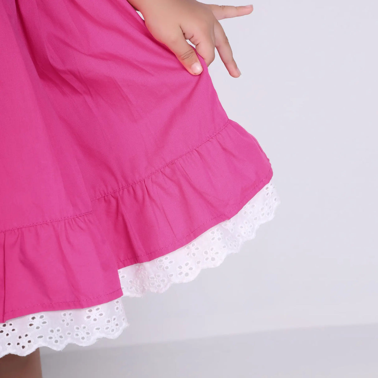 Close-up of the hem details on the pink cotton puffed sleeves dress.