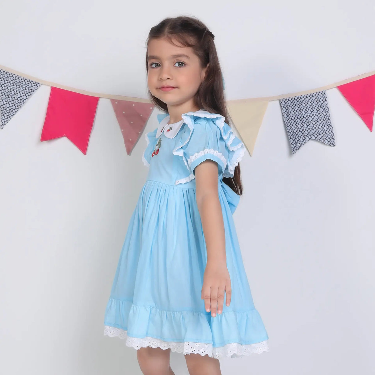 Side view of a girl in a blue embroidered cotton puffed sleeves dress.