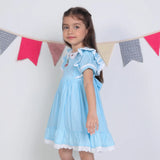 Side view of a girl in a blue embroidered cotton puffed sleeves dress.