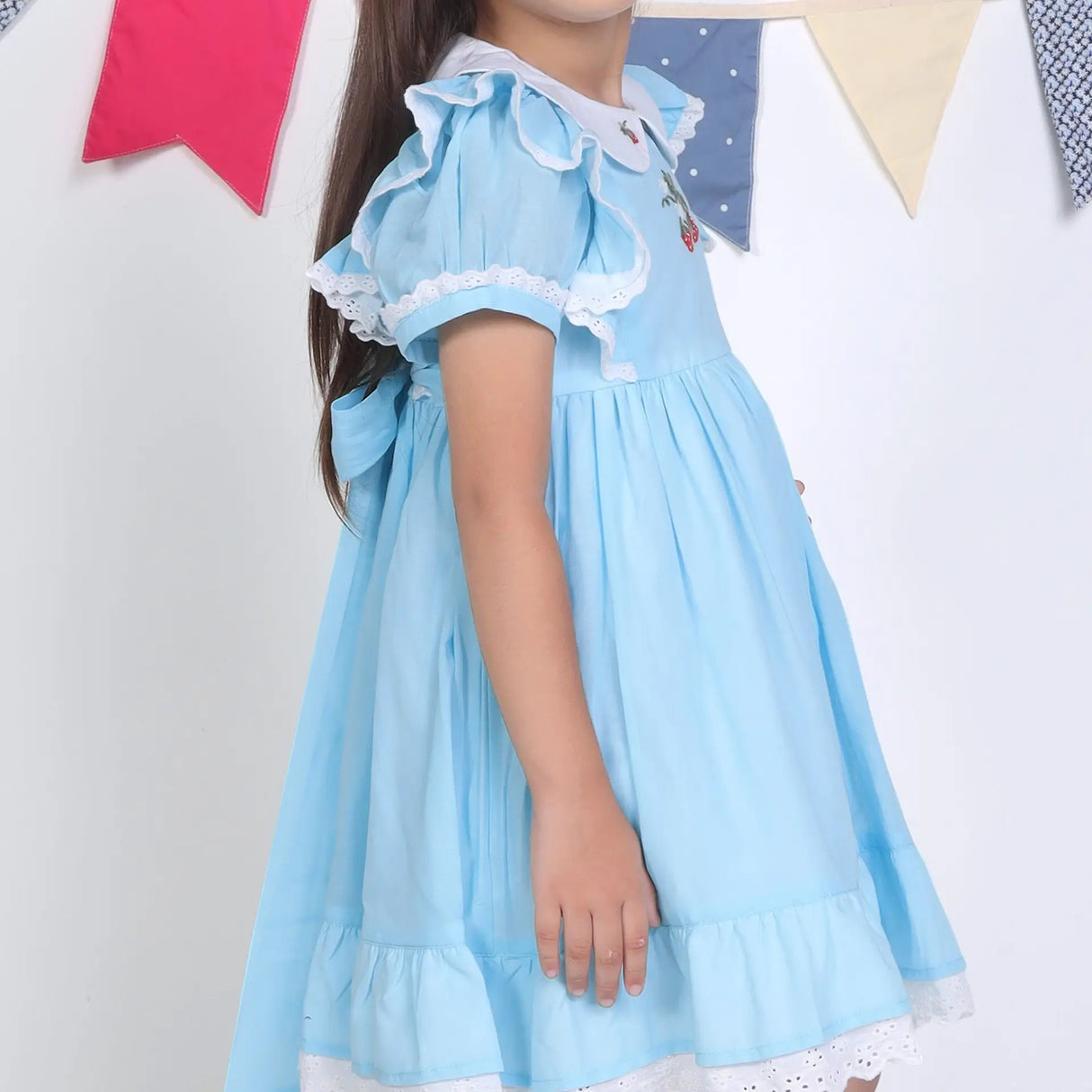 Side view of a girl in a blue embroidered cotton puffed sleeves dress.