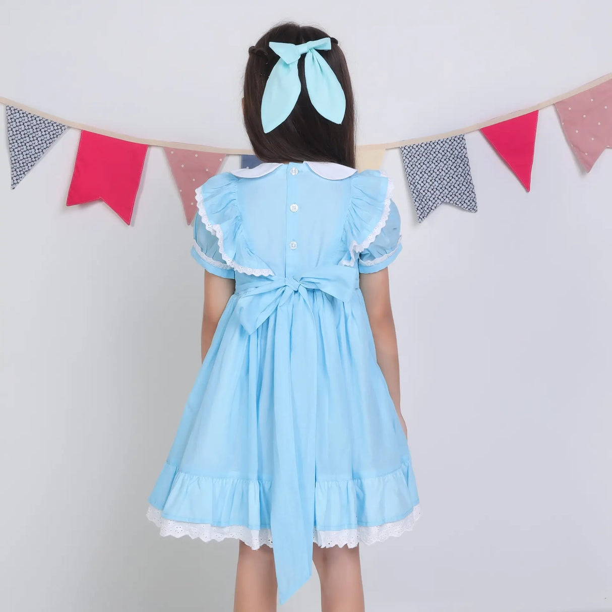 Back view of a girl in a blue embroidered cotton puffed sleeves dress.