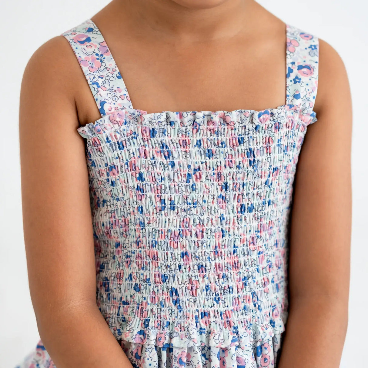 Close-up of the smocked bodice of a white floral printed strappy dress.