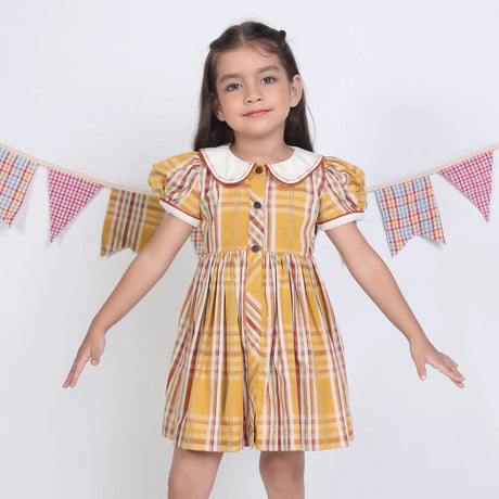 A girl dressed in a mustard checked embroidered cotton puffed sleeves dress.