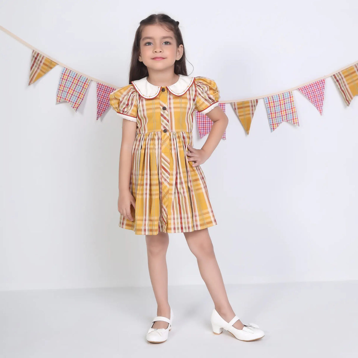 A girl posing in a mustard checked embroidered cotton puffed sleeves dress.