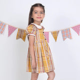 Side view of a girl in a mustard checked embroidered cotton puffed sleeves dress.