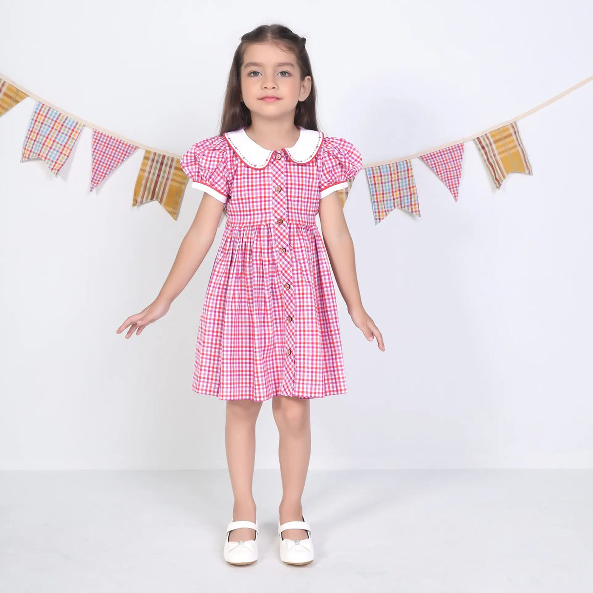 A girl dressed in a pink checked embroidered cotton puffed sleeves dress.