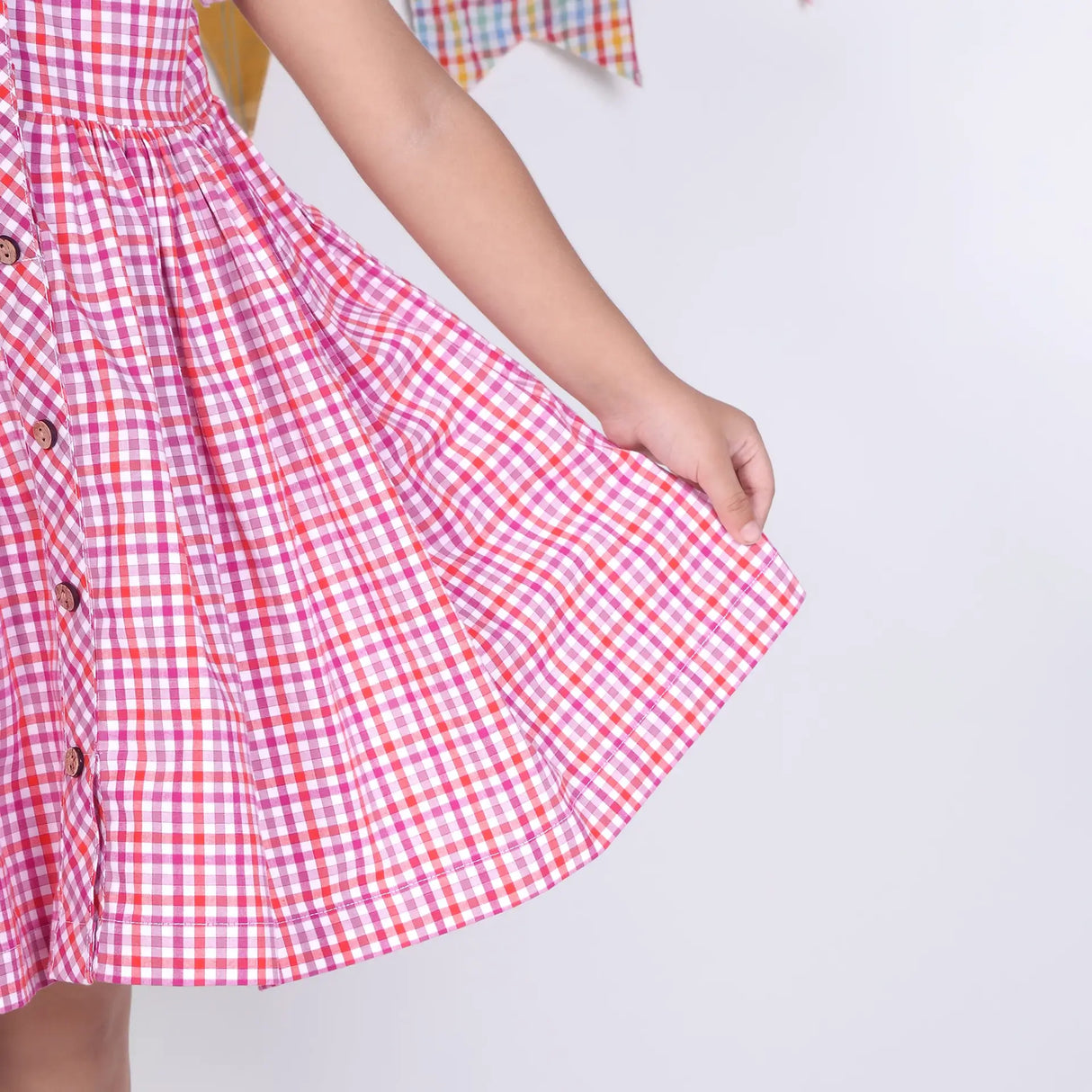 Close-up of the skirt in a pink checked embroidered cotton puffed sleeves dress.