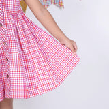 Close-up of the skirt in a pink checked embroidered cotton puffed sleeves dress.