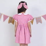 Back pose of a girl in a pink checked embroidered cotton puffed sleeves dress.