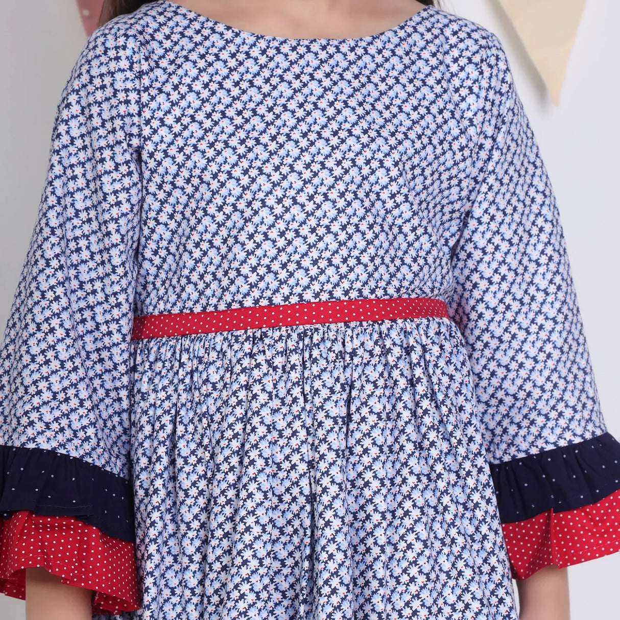 "Close-up of a girl dressed in a navy floral printed cotton long ruffled sleeves dress."