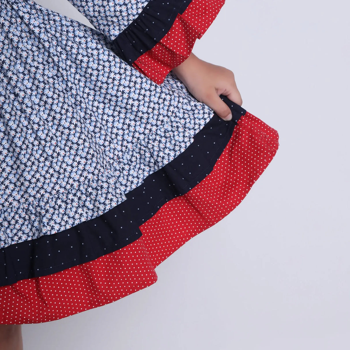 "Close-up of the layer details in a navy floral printed cotton long ruffled sleeves dress."