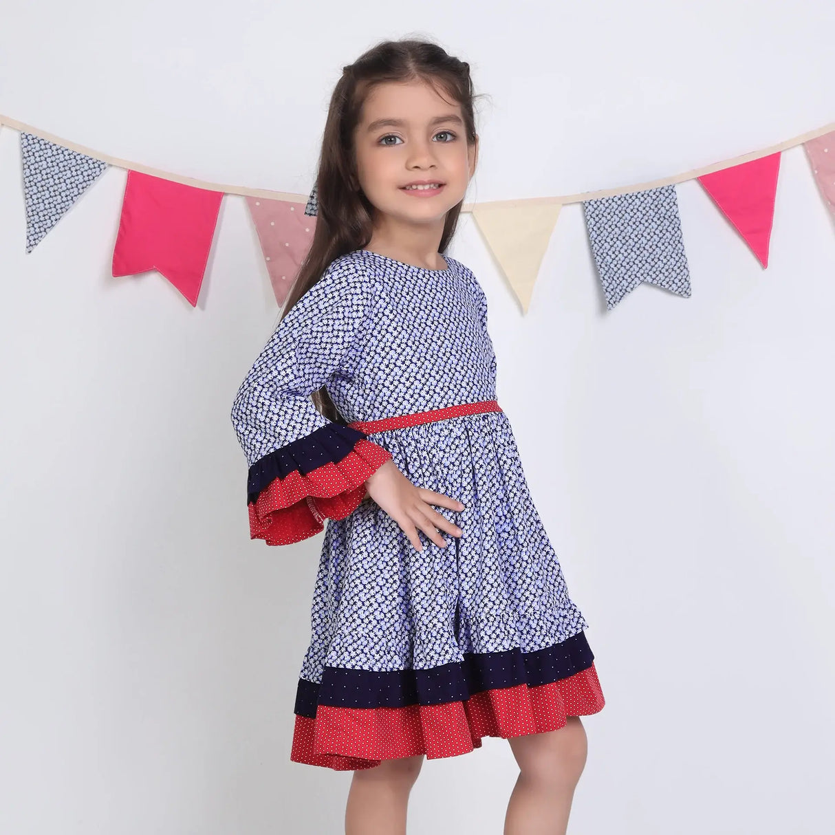 "Side pose of a girl in a navy floral printed cotton long ruffled sleeves dress."