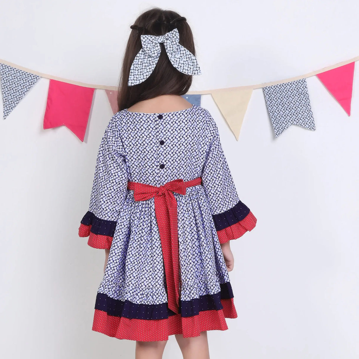"Back pose of a girl in a navy floral printed cotton long ruffled sleeves dress."