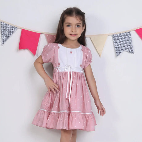 "A little girl posing in a pink embroidered cotton dot printed dress."